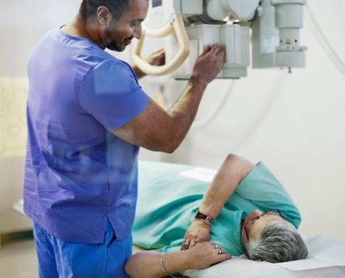 Radiologist giving a woman an xray using a fixed xray machine
